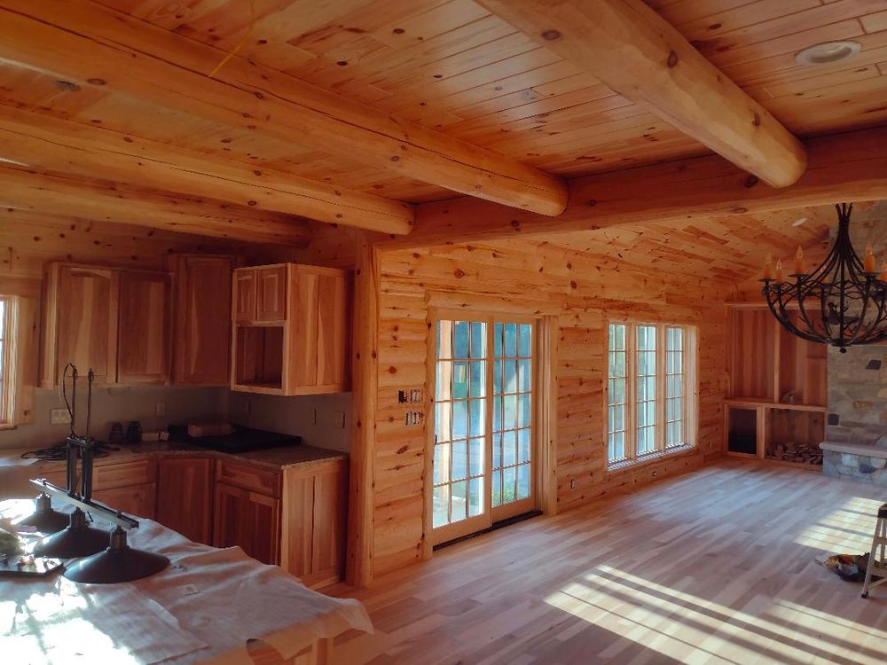 Wood interior with vaulted ceiling, large windows, and warm finish carpentry details